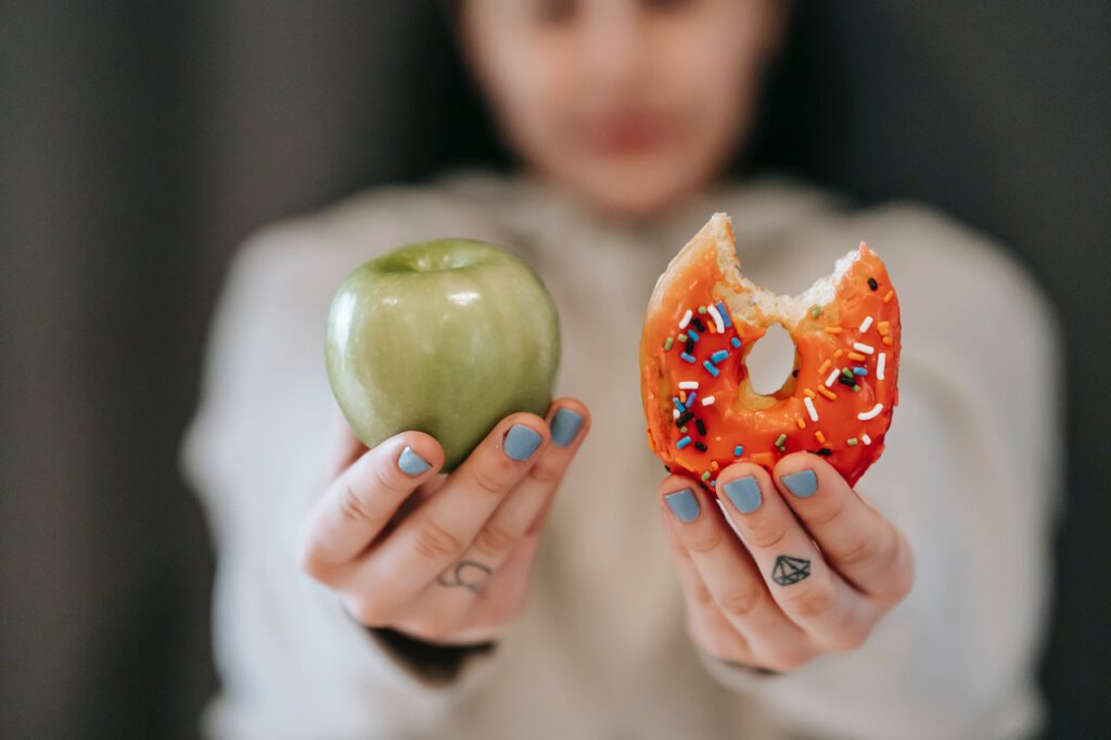 Woman holding an apple and donut in her hands