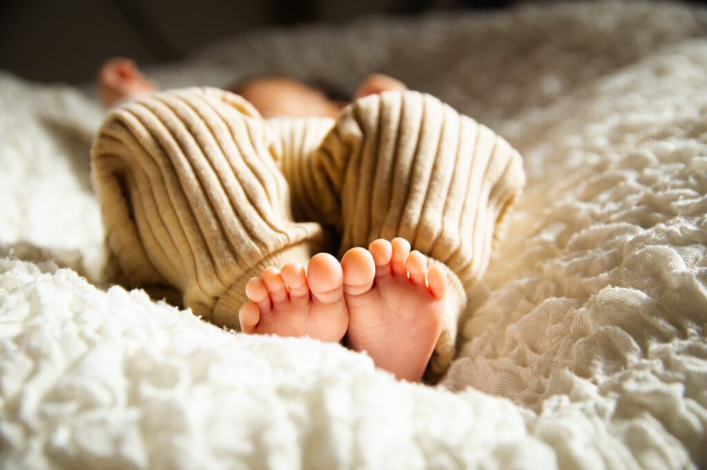Newborn baby is laying on the blanket with bare feet